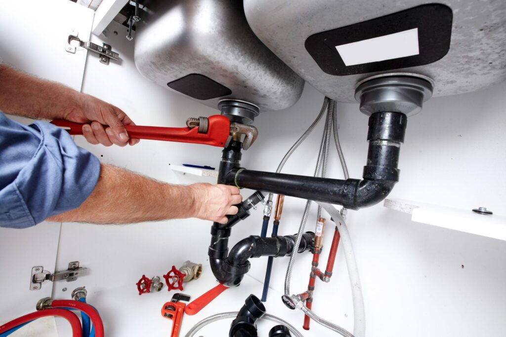 Plumber repairing drain pipes beneath a kitchen sink in Lemon Grove
