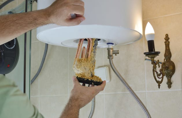 Technician removing mineral buildup from a water heater in Lemon Grove